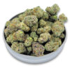 Close‑up of frosty Ice Cream cannabis smalls piled in a round metal lid, showing dense green and purple buds coated in trichomes on a white background.